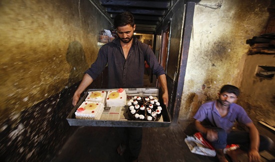 Một người thợ làm bánh ở Kashmir tấn bật chuẩn bị bánh và đi giao hàng trước ngày diễn ra Lễ hội thánh Eid-al-Fitr.