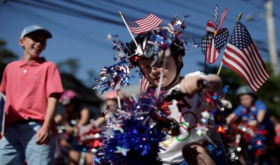 Một cậu bé lái chiếc xe đạp được trang trí rực rỡ qua ngôi làng Barnstable, Massachusetts, trong buổi diễu hành lễ kỷ niệm Quốc khánh.
